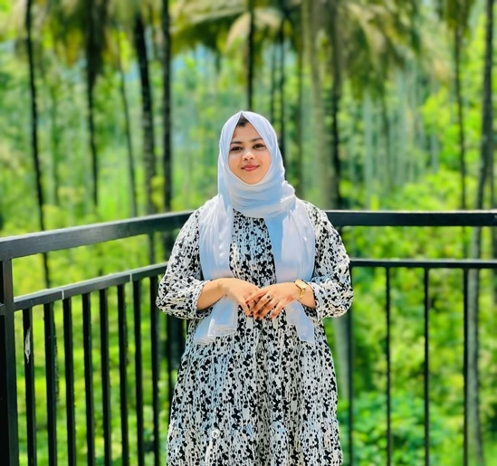 best digital marketing strategist in malappuram stands on a balcony with a black railing, surrounded by lush green trees and a scenic natural backdrop.